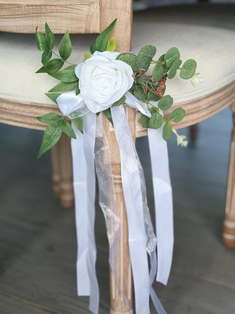 A chair tie, one open ivory rose and eucalyptus with satin tails