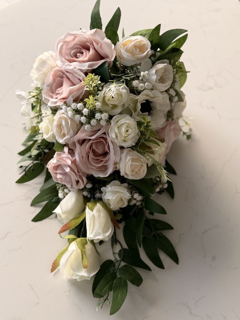 A trailing teardrop bouquet of blush and ivory roses
