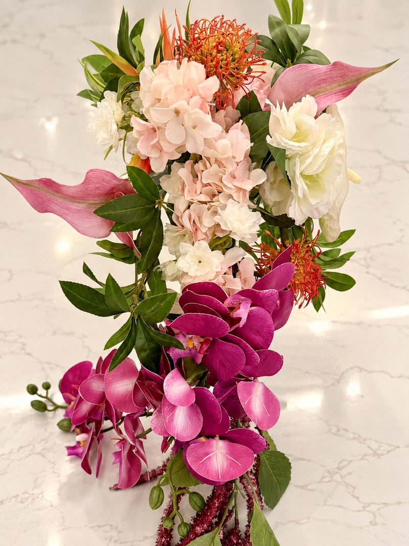A tropical cascade of pink calla lilies, orange protea, orchids and trailing amaranthus